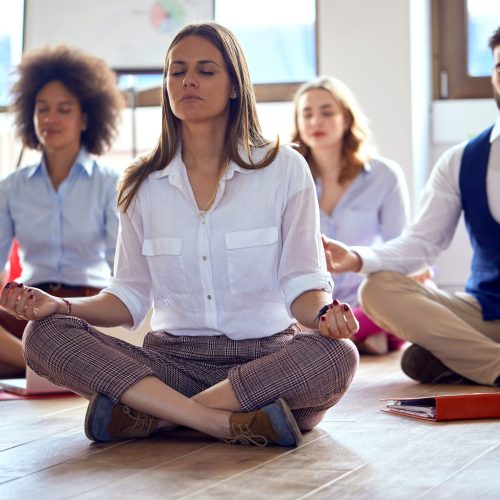 Young colleagues having yoga and relaxing in the office